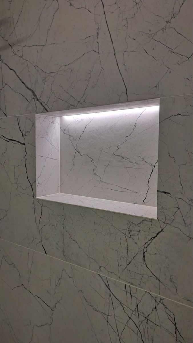 Large-format marble-look tile with a lit niche