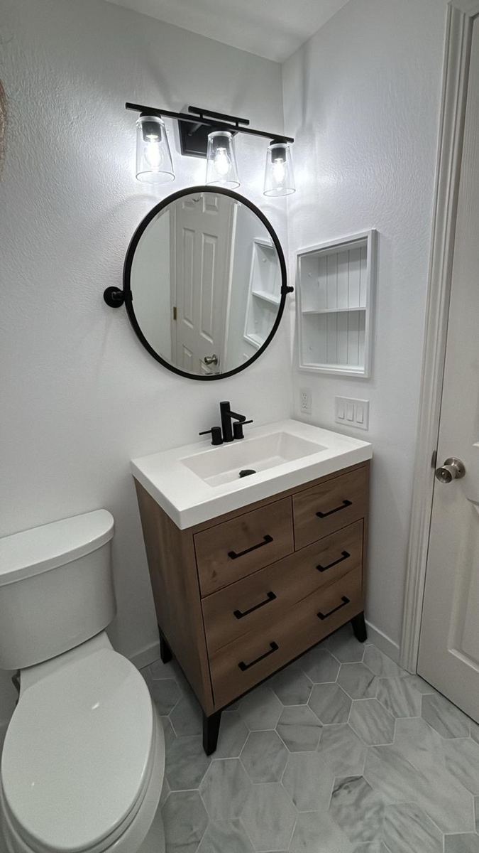 Wood vanity, round mirror and marble-look floor