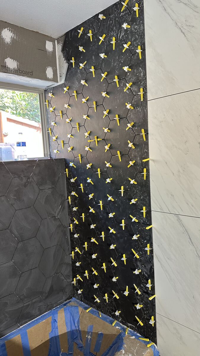 Large-format tile being set with leveling clips on a TrueSquare project